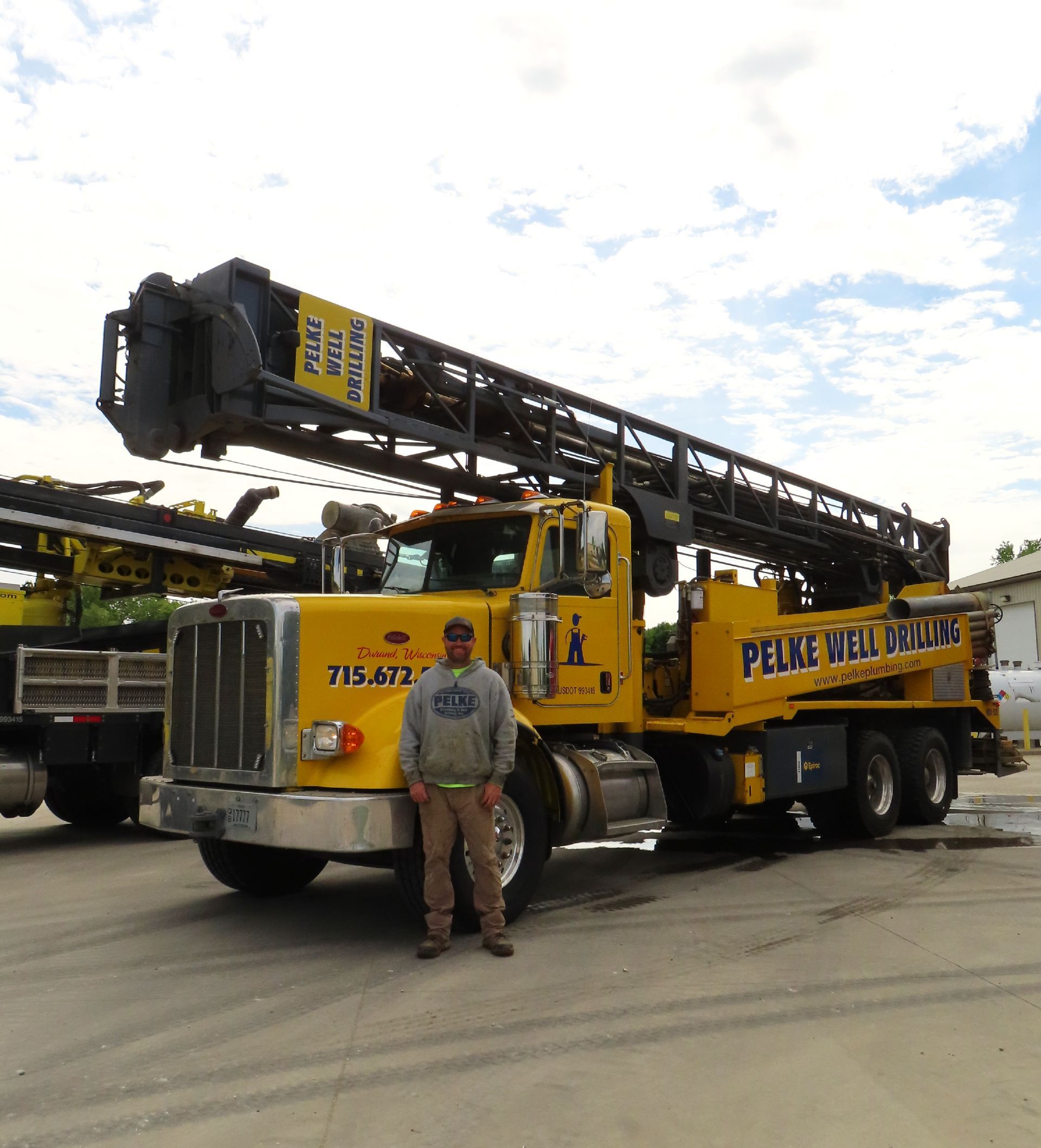 Yellow Peace River crane truck with a man standing in front on a lot