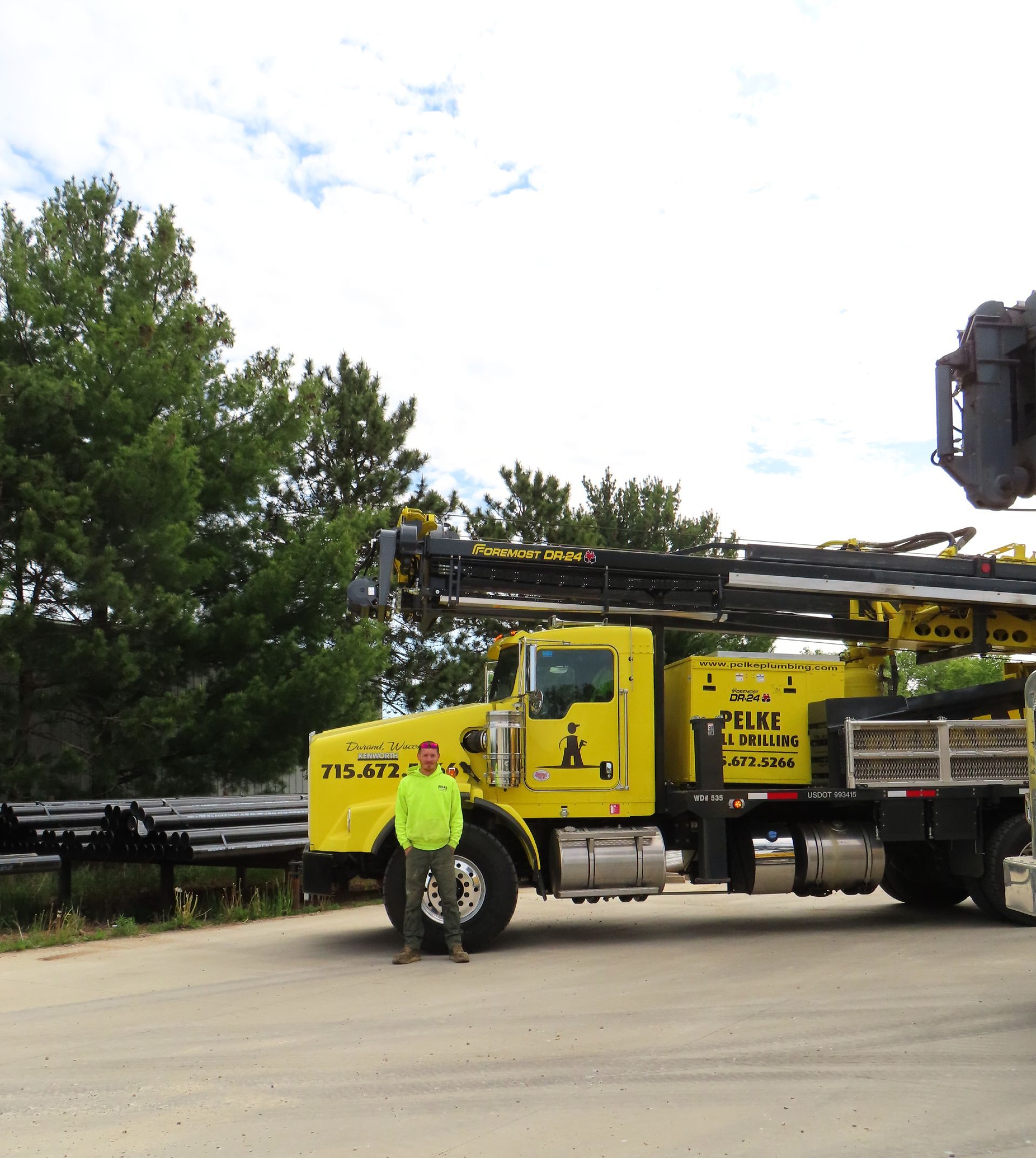 Yellow drilling truck parked on a road with trees in the background