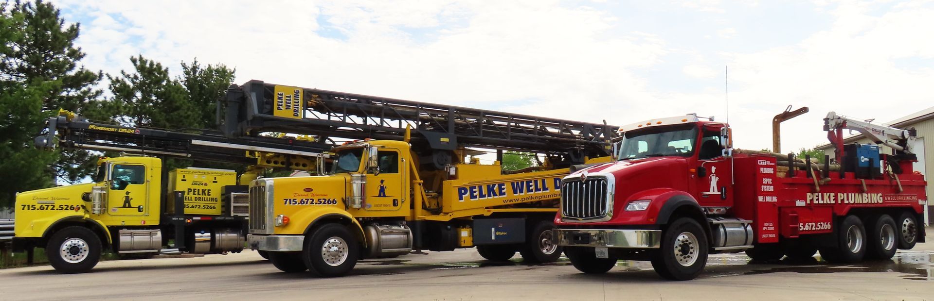 Yellow and red utility trucks parked in a row under a cloudy sky