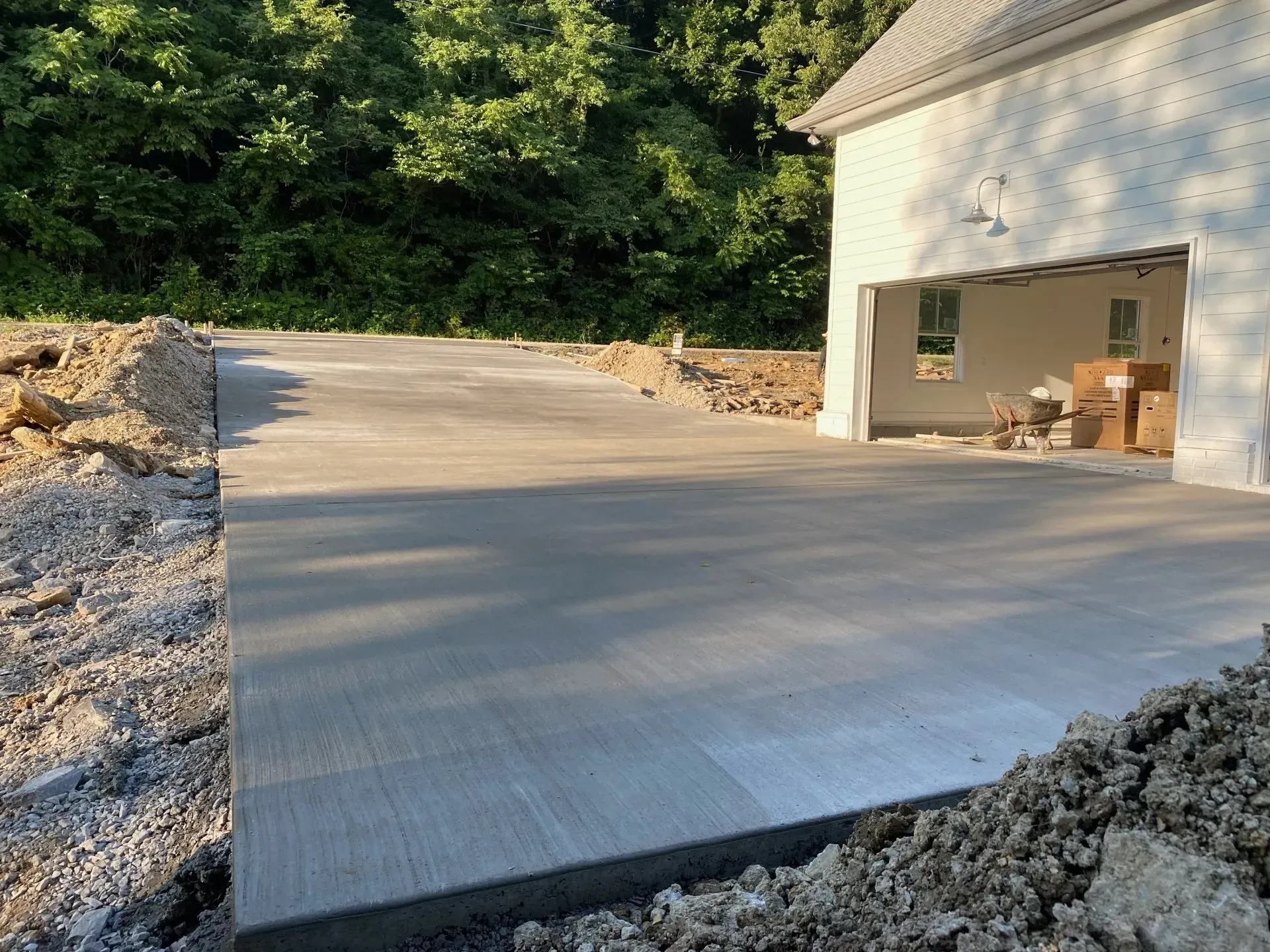 Newly poured concrete driveway leading to a garage entrance, with trees in the background.