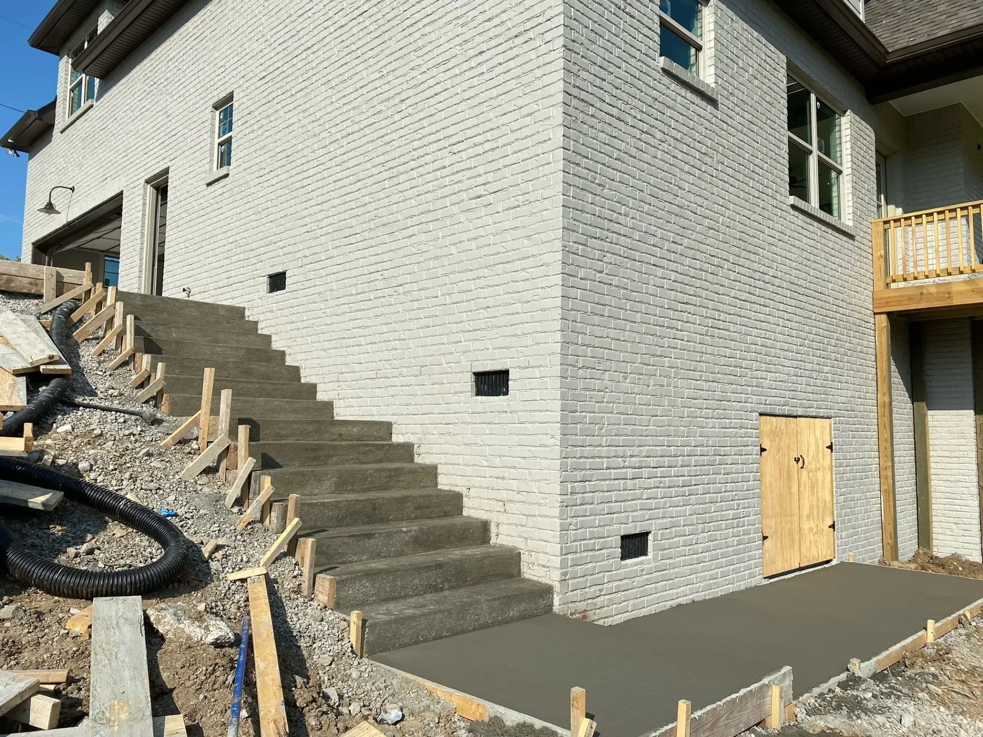 Concrete steps and landing under construction next to a brick building. Wooden forms visible.