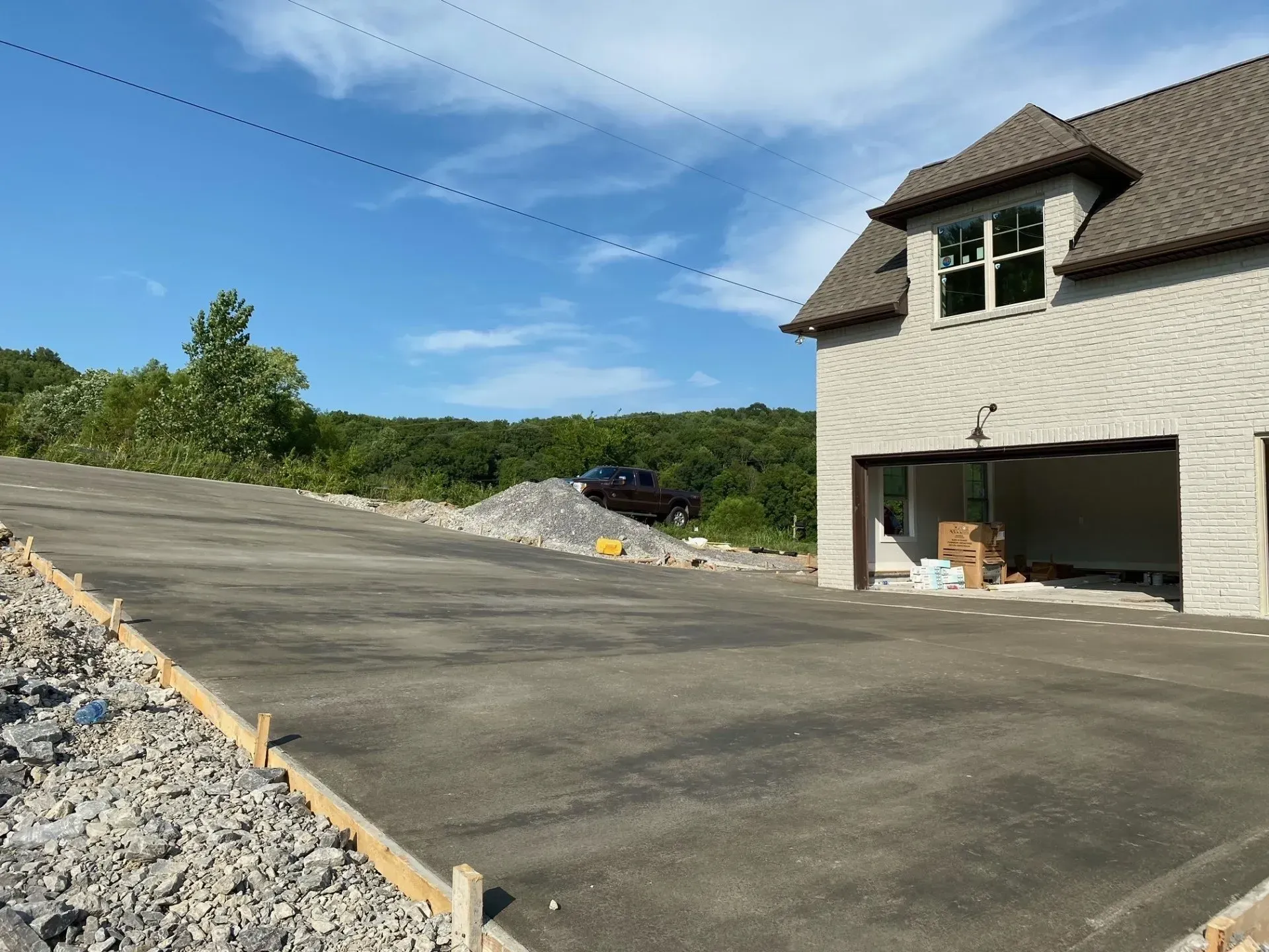 Concrete driveway with a house under construction; blue sky and trees in the background.