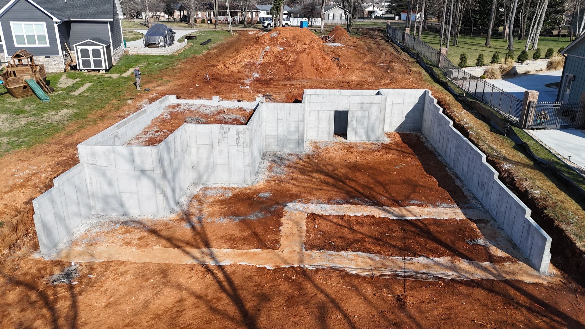 Concrete foundation walls of a new house under construction on a dirt lot.