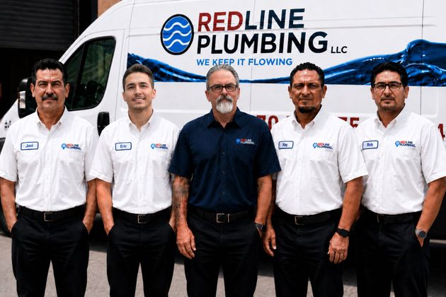 Five Redline Plumbing employees standing in front of a company service van