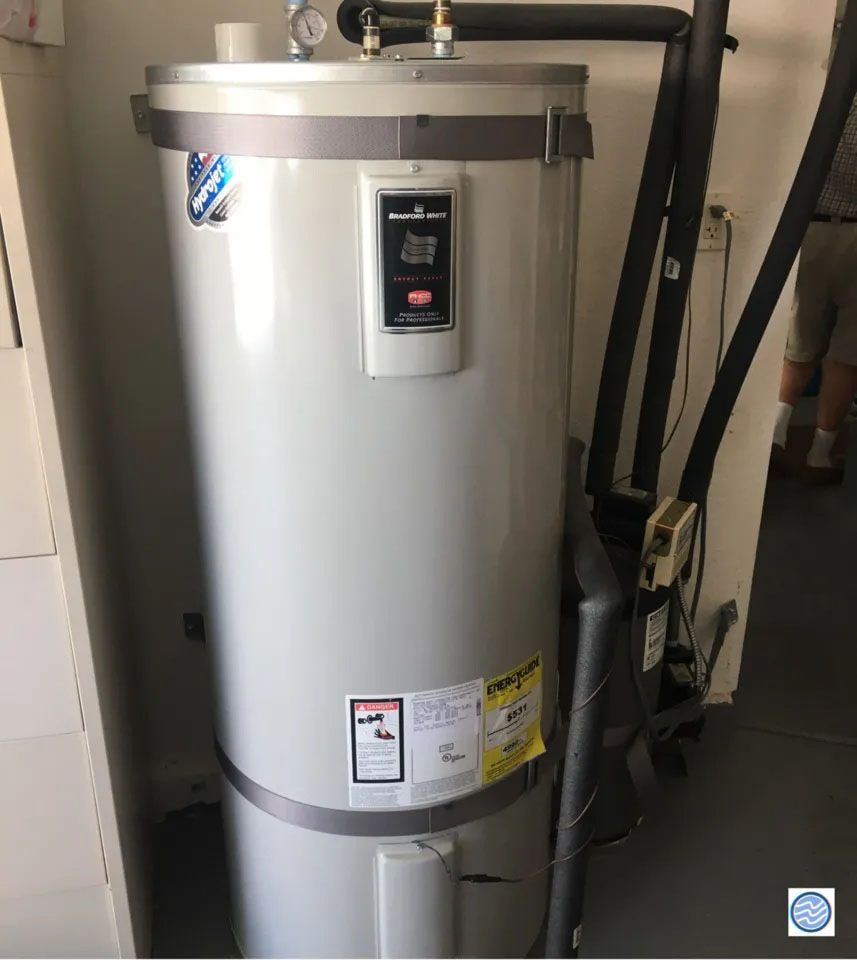 White water heater tank in a utility area, with pipes and a control panel.