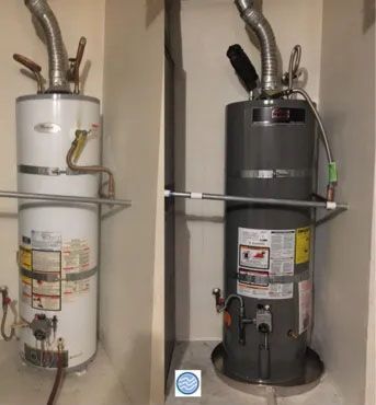 Side-by-side water heaters: old white tank and newer dark gray tank in a utility closet