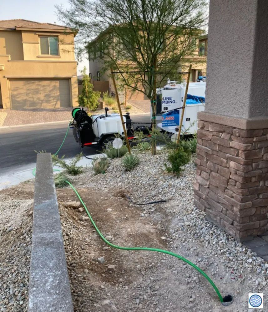 Front yard with landscaping tools and a green hose near a stucco house under construction or maintenance.