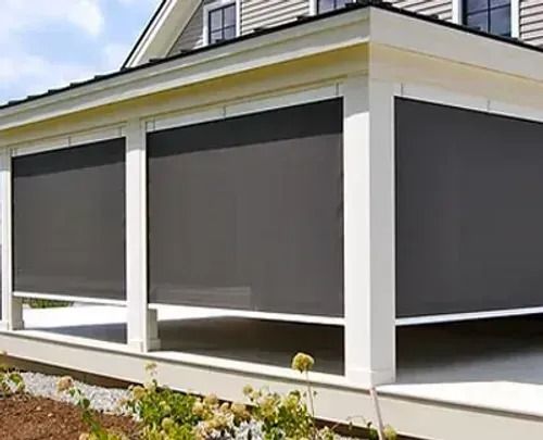 House porch with gray roll-down shades covering large windows and white trim.