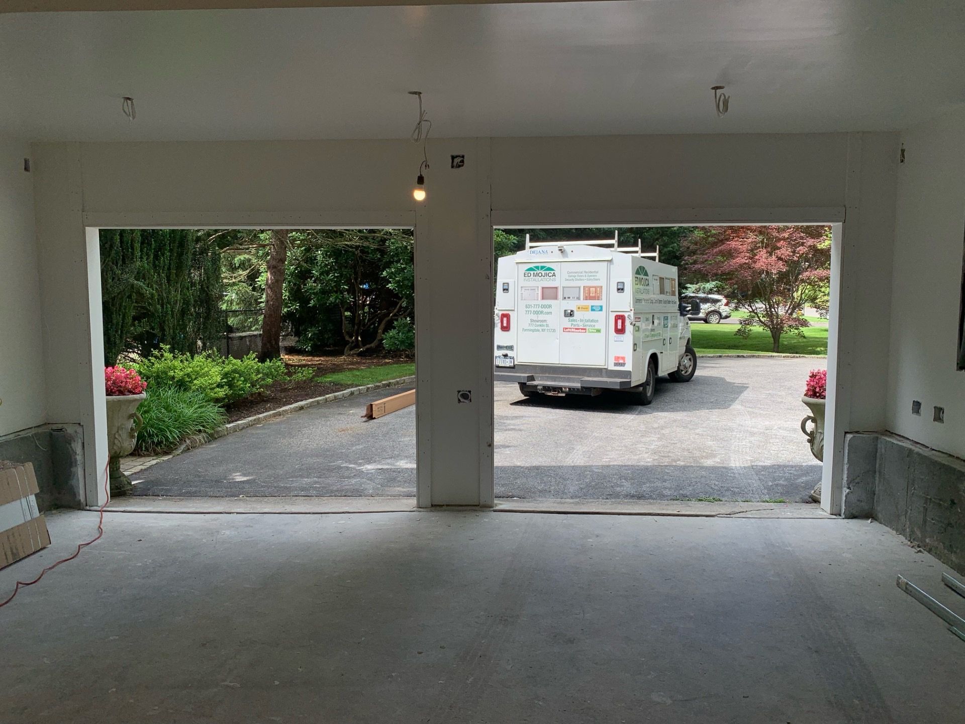 Open garage interior with a view of a driveway, service truck, and landscaping.