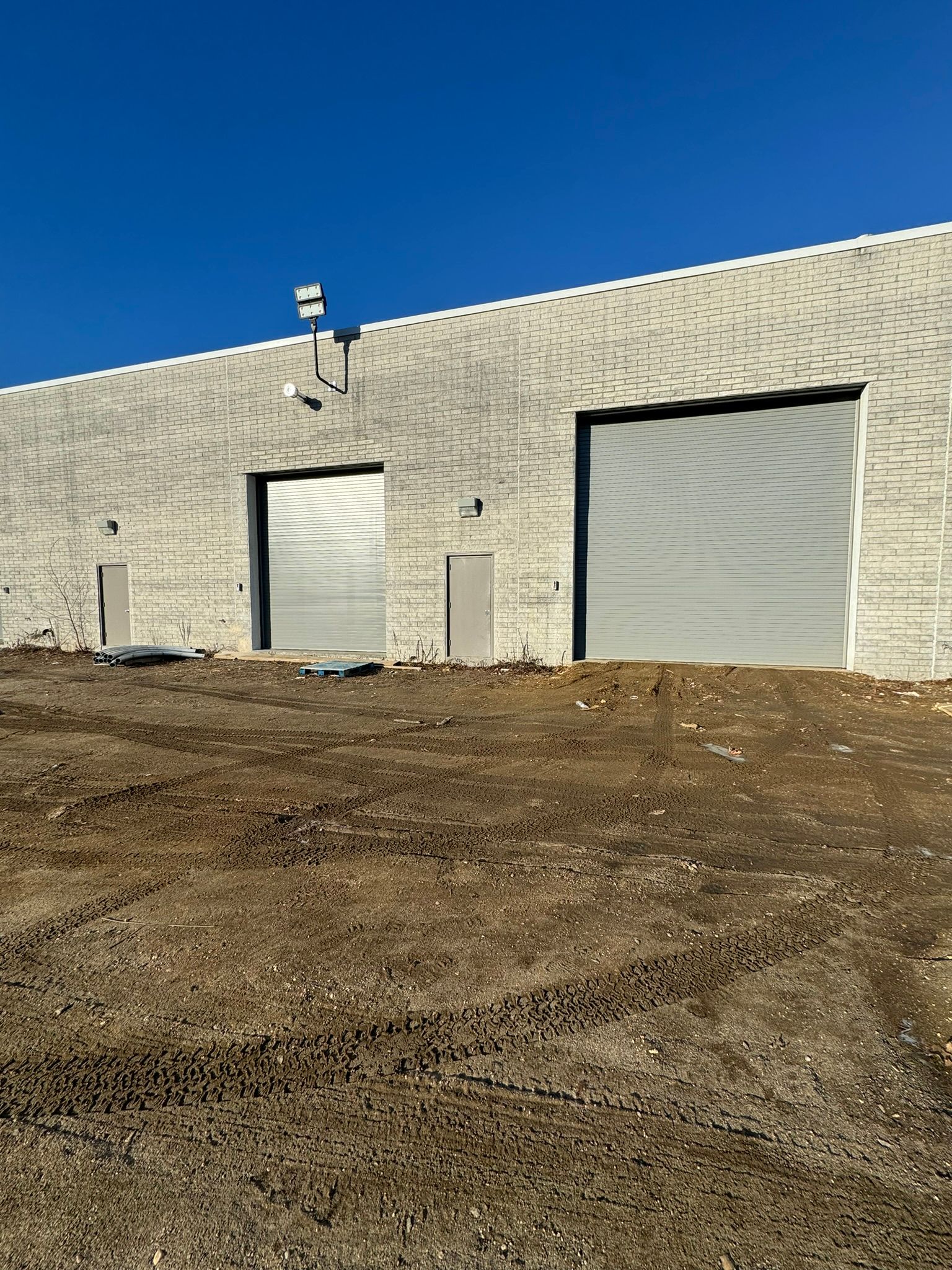 Exterior of a commercial building with gray roller doors on a sunny day.