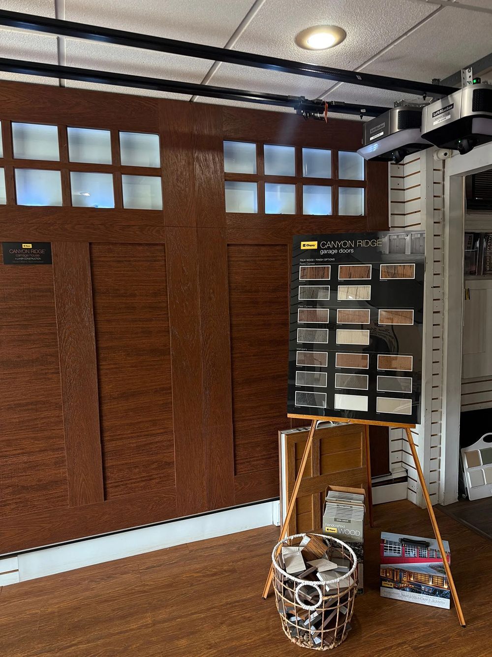 Garage door display featuring various finishes, samples, and color options in a showroom setting.