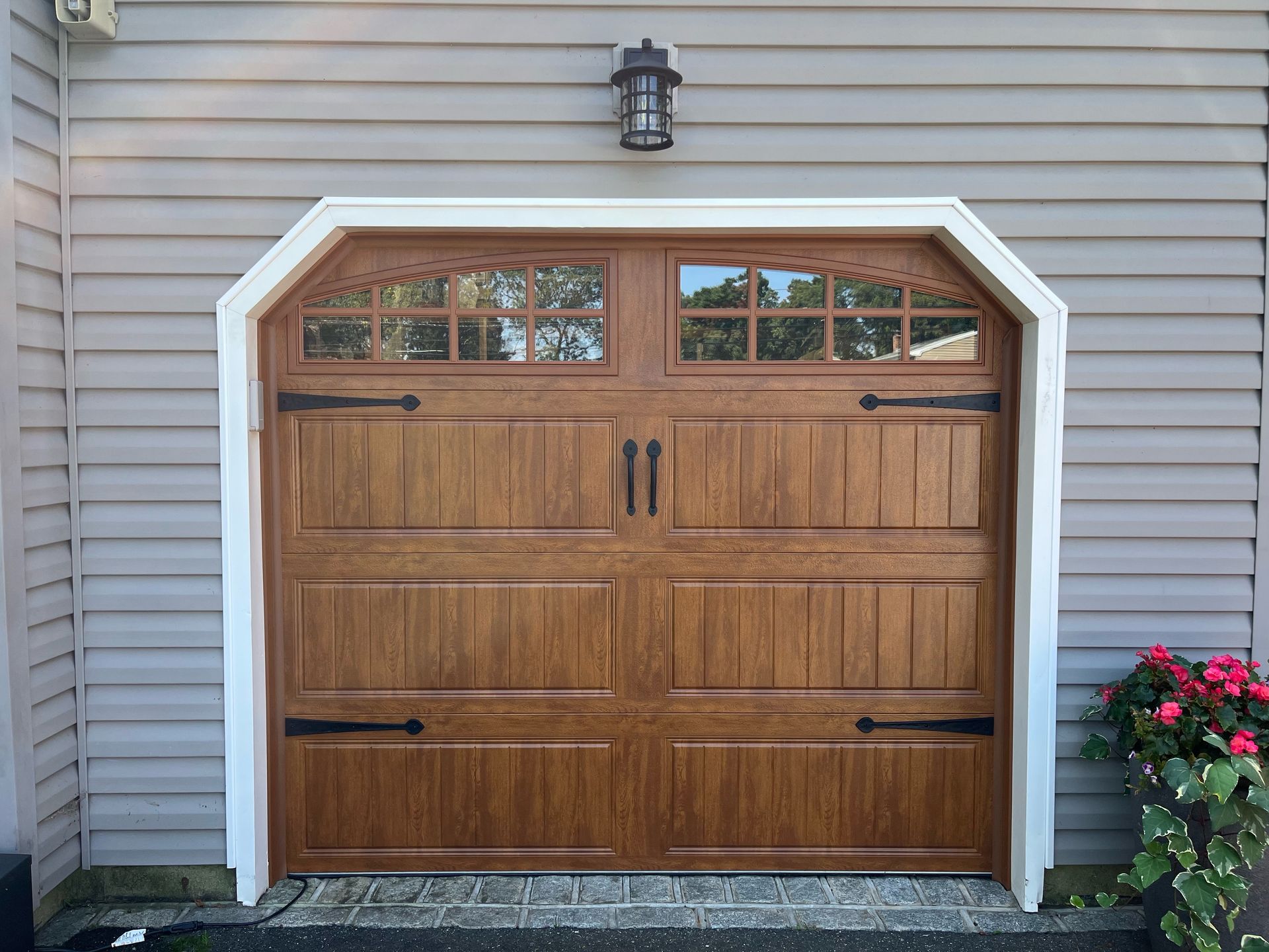 Wooden garage door with window panels, white trim, and a black light fixture.