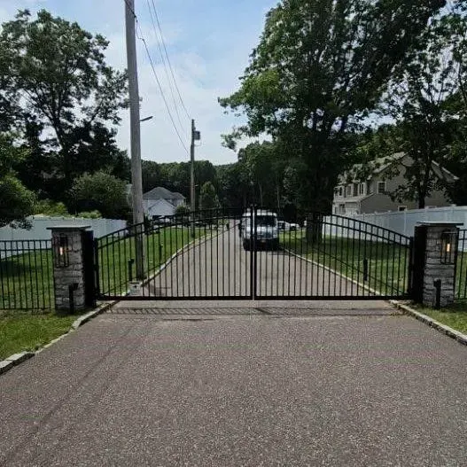 Black metal gates at the entrance to a long driveway.