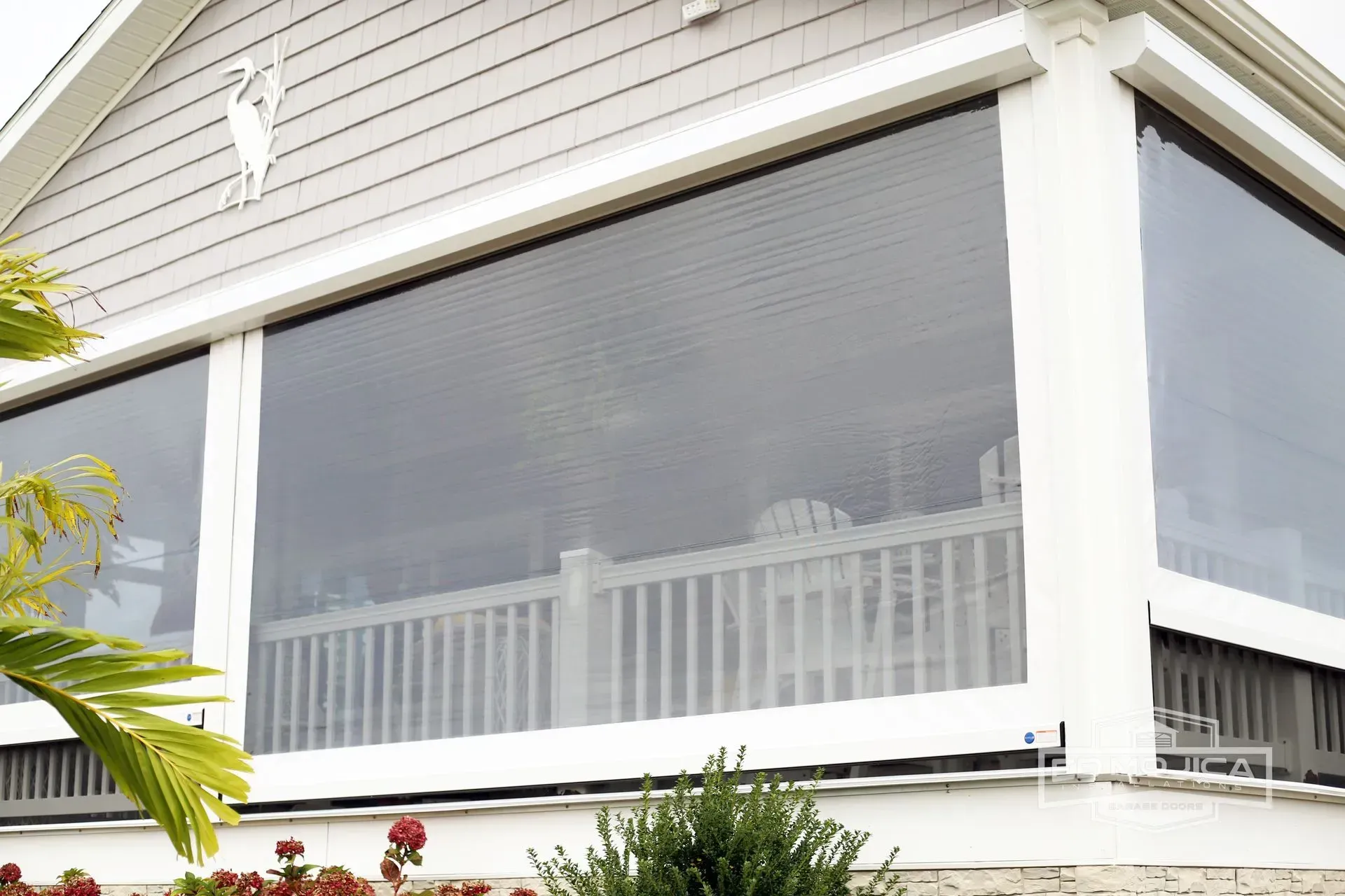 Clear vinyl patio enclosures on a white porch, providing protection and visibility.