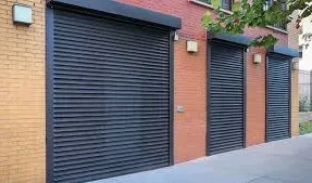Three black rolling shutters on a brick building exterior.