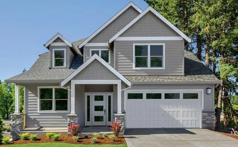 Two-story gray house with white trim, a garage door, and a front porch, in a sunny setting.