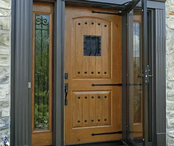 Wooden front door with sidelight and screen door, all framed in dark metal.