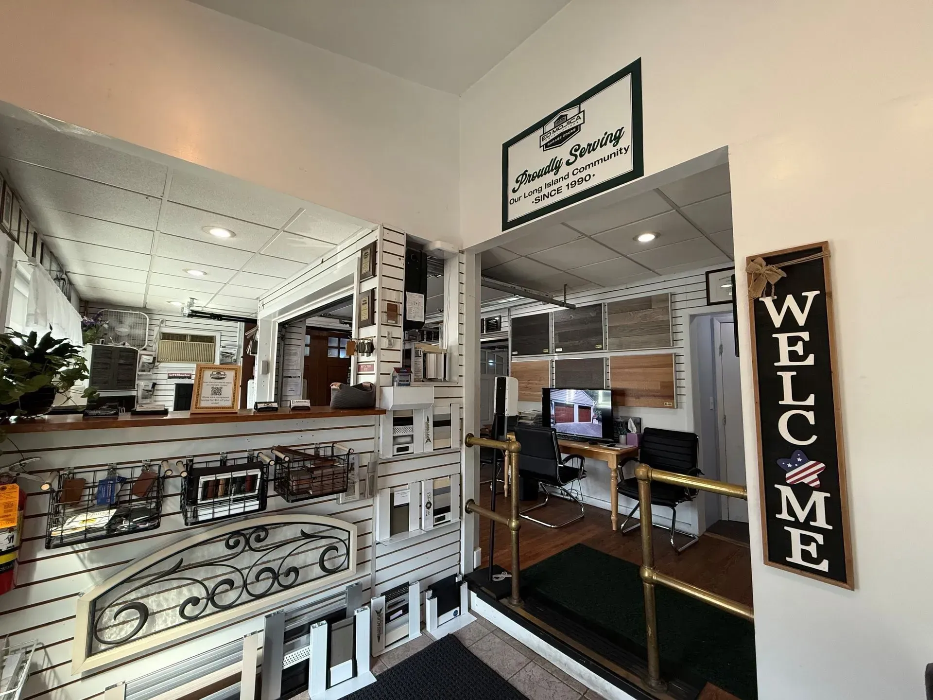 Interior view of a business entrance; a welcome sign, display racks, and a desk with a computer.
