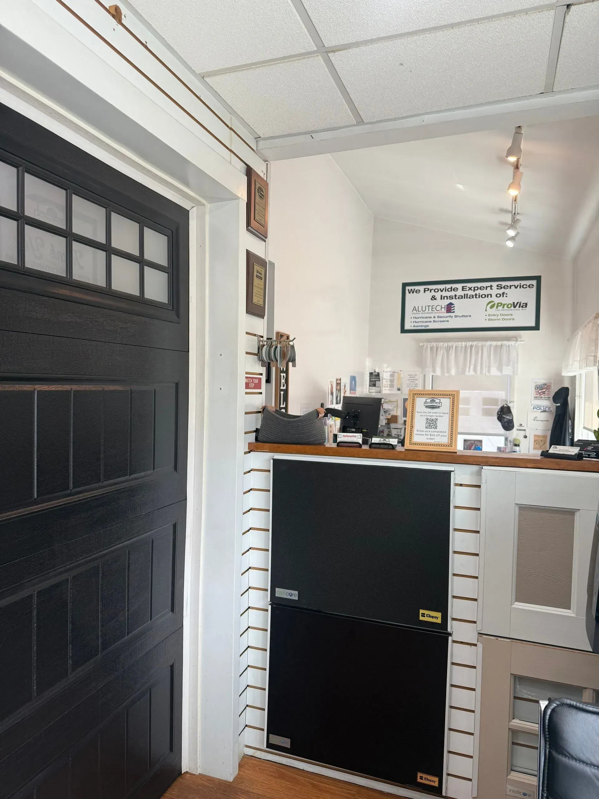 Interior with a black door, white walls, and a counter area with a sign and various items.