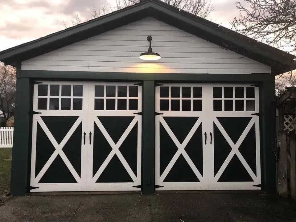 Green and white garage doors with an X design, lit by a single overhead light.