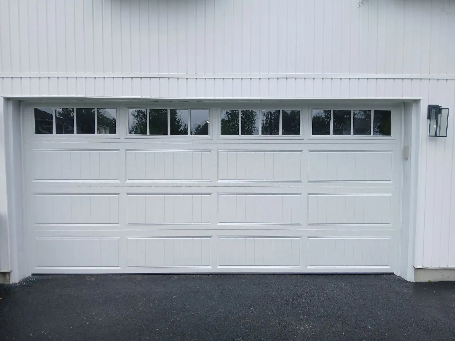 White garage door with windows above, set in white building.