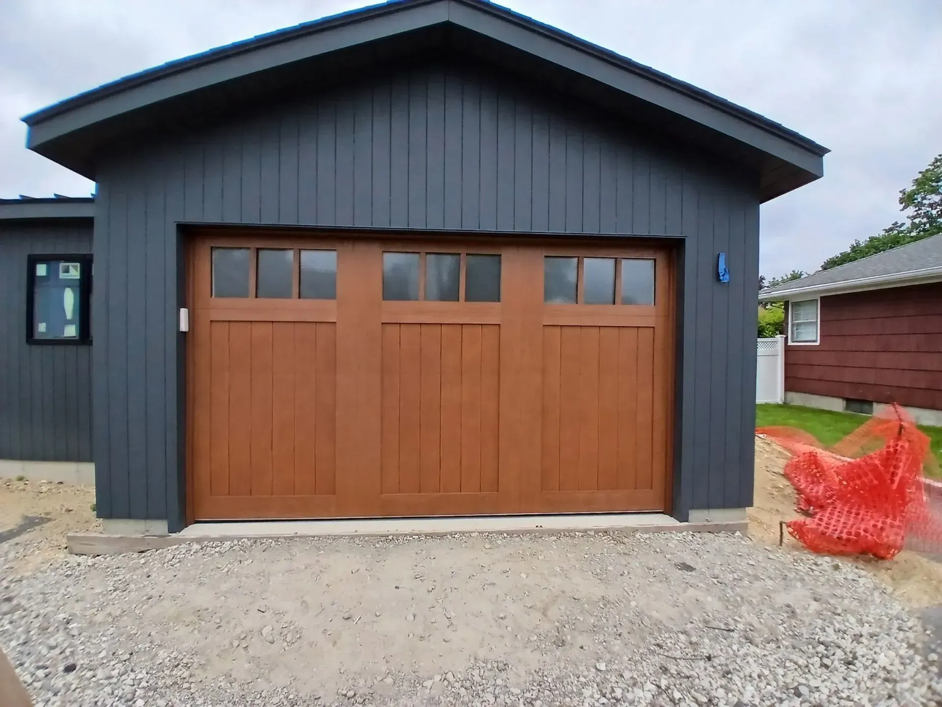 Brown garage door on a dark gray building with a concrete base.
