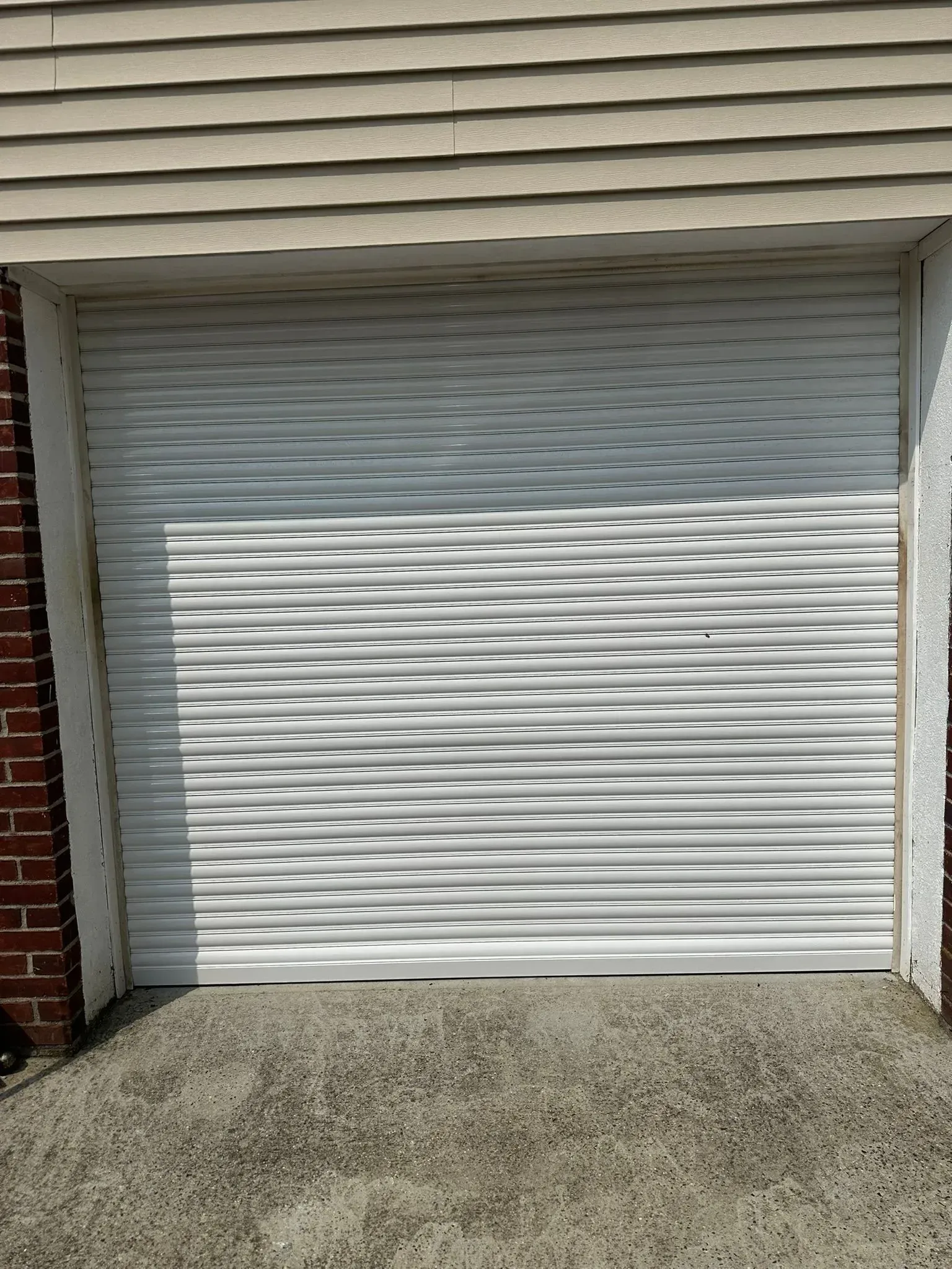 White textured garage door in front of a building with gravel in front.