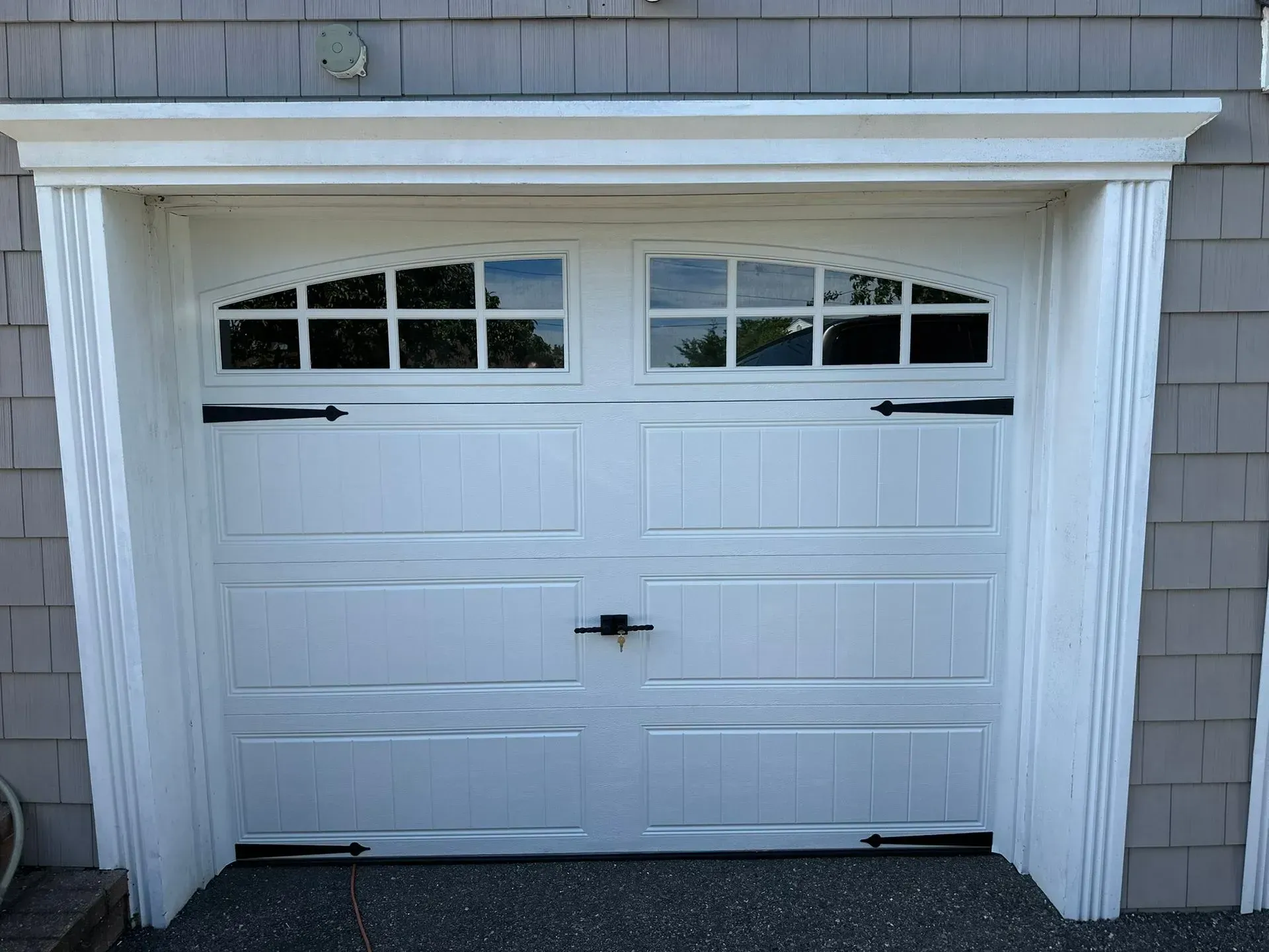 White garage door with arched window panels and decorative trim.