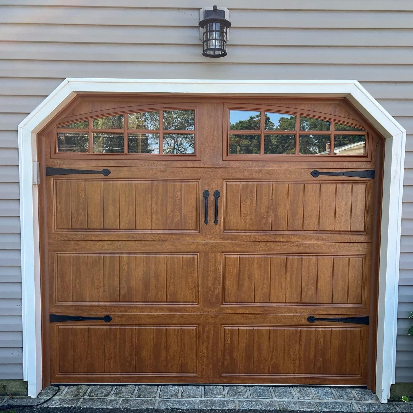 Brown garage door with windows and decorative hardware, set in white trim.