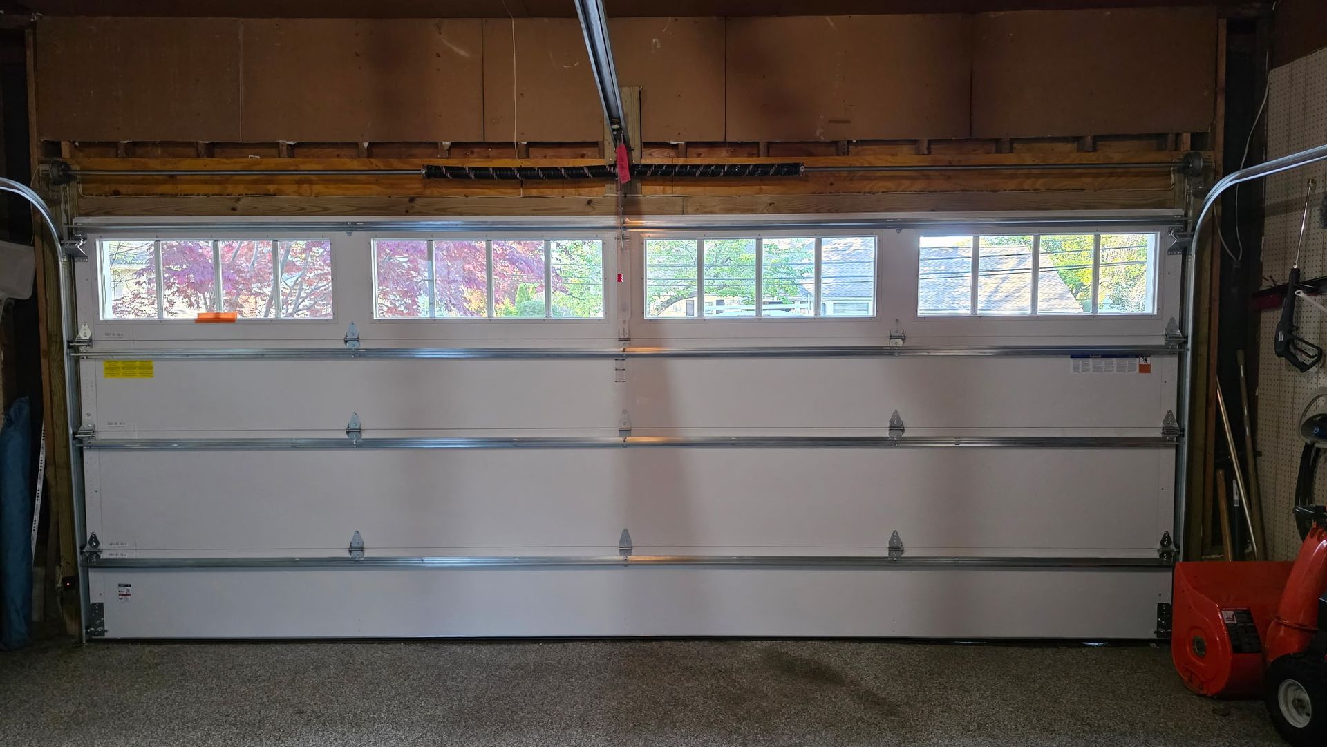 White sectional garage door inside a garage, with small windows along the top.