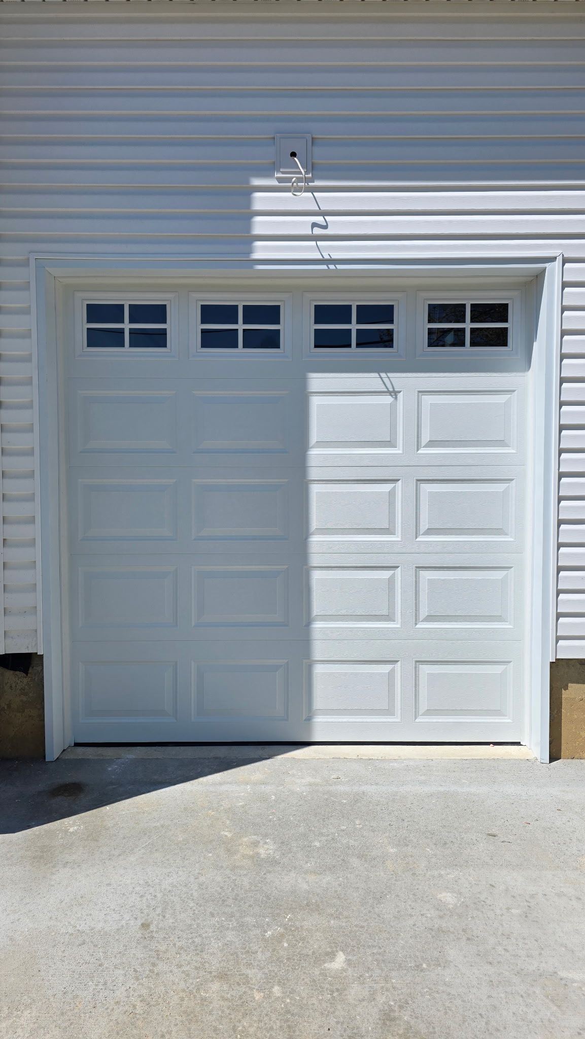 White garage door with small windows in front of gray siding.