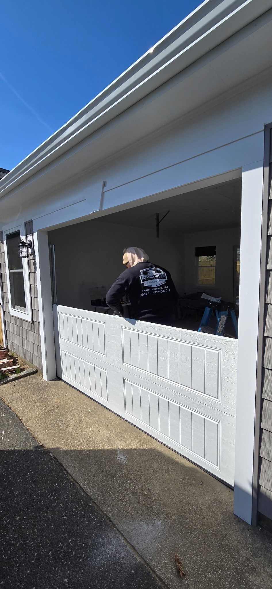 Person leaning through a service window of a white building under a sunny sky