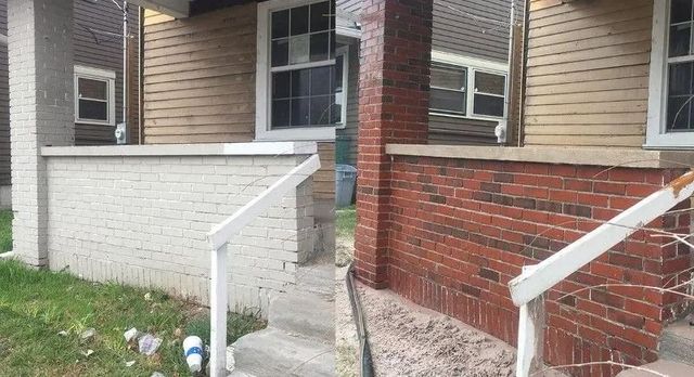 Front steps to a house with white and red brick walls and white railing on each side