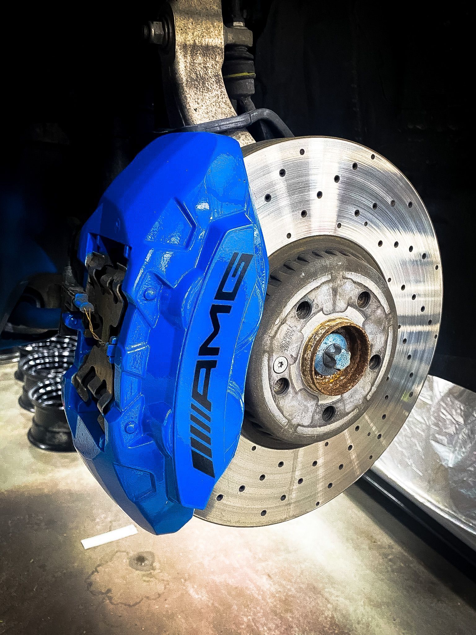 A close up of a blue amg brake caliper on a car.