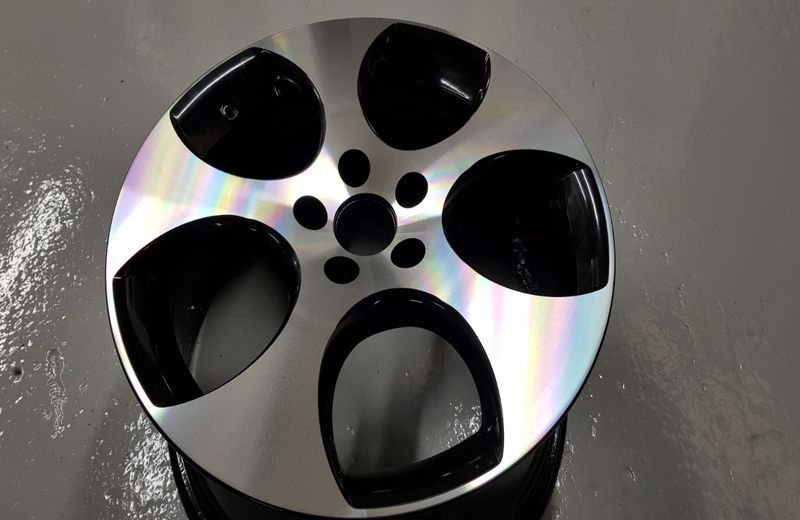 A close up of a black and silver wheel on a white surface