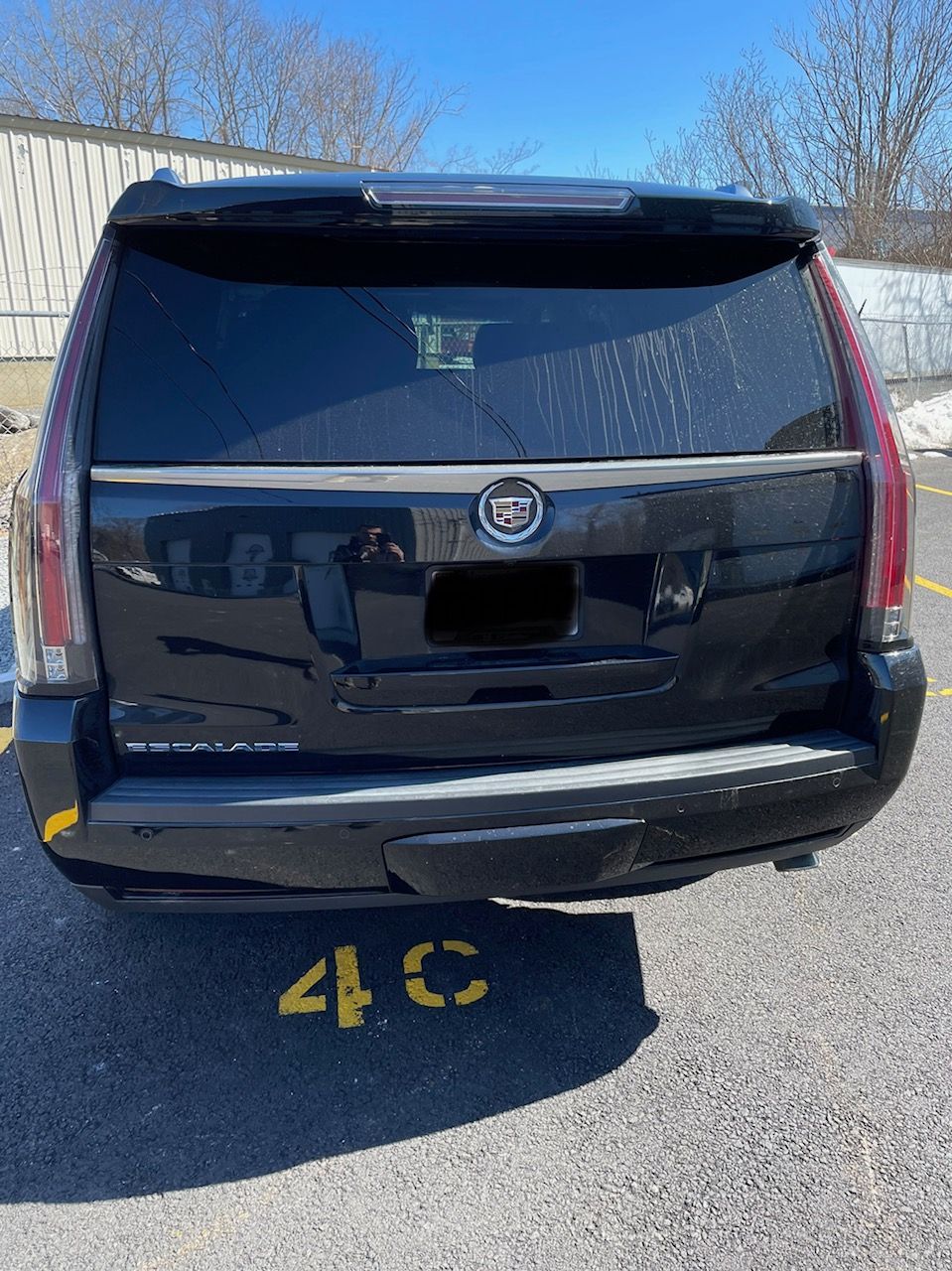 A black cadillac escalade is parked in a parking lot.