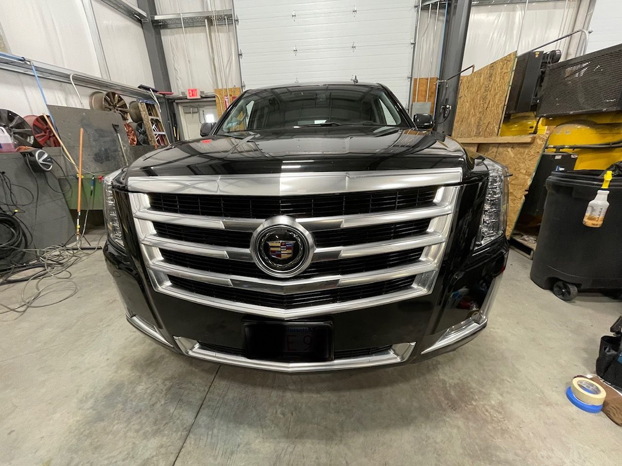 A black cadillac escalade is parked in a garage.