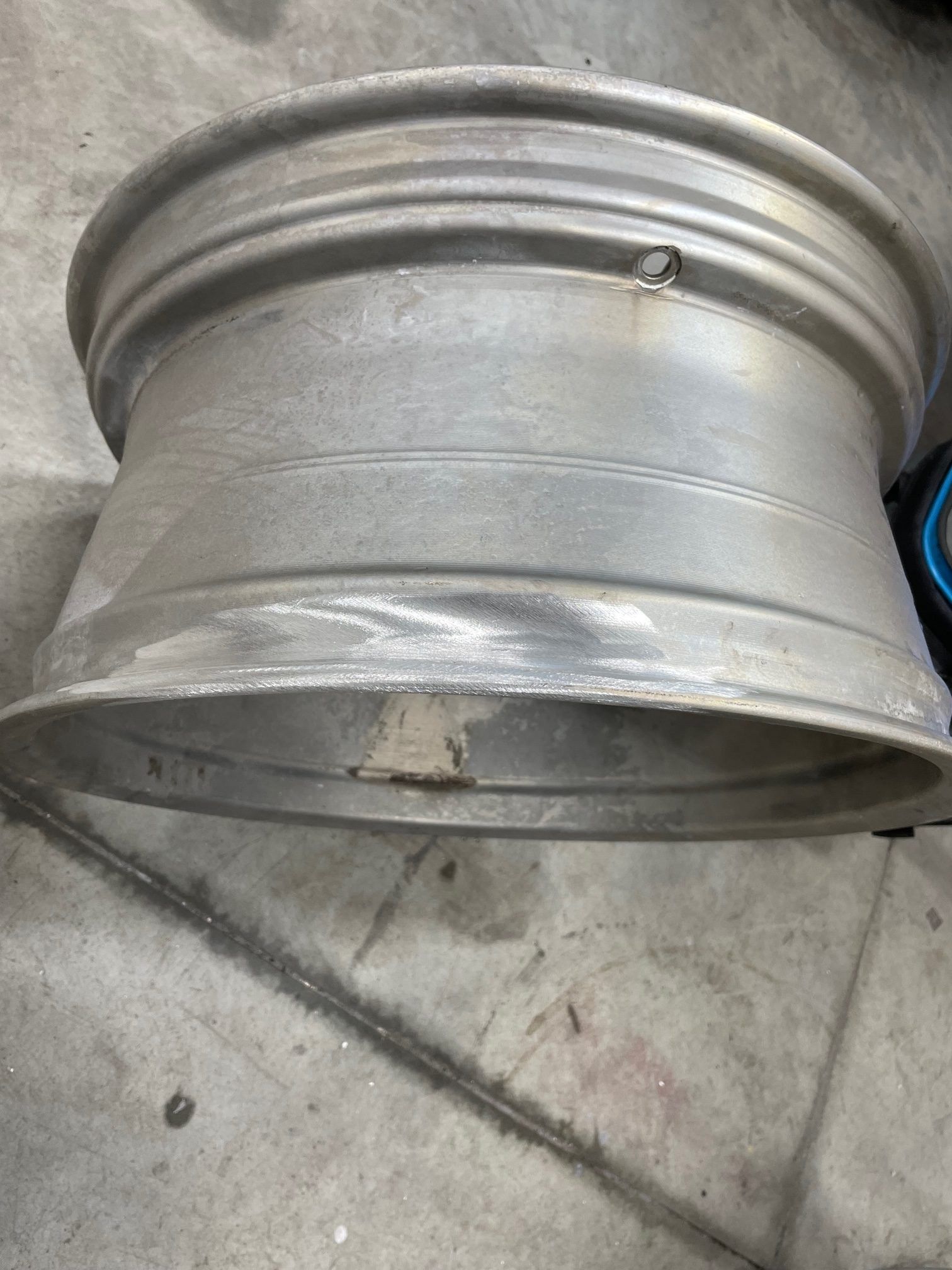 A metal wheel is sitting on a concrete floor.