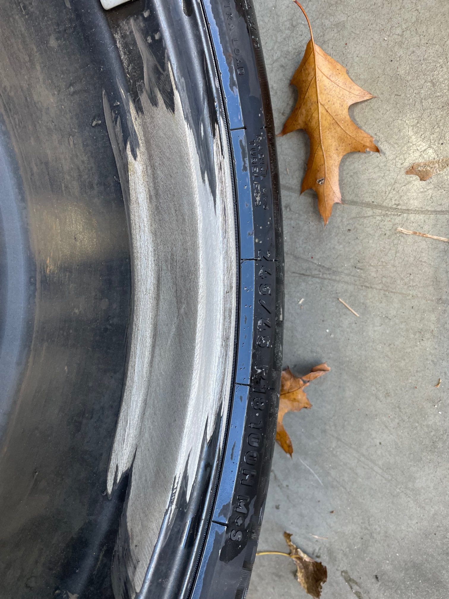 A close up of a tire with leaves on the ground.