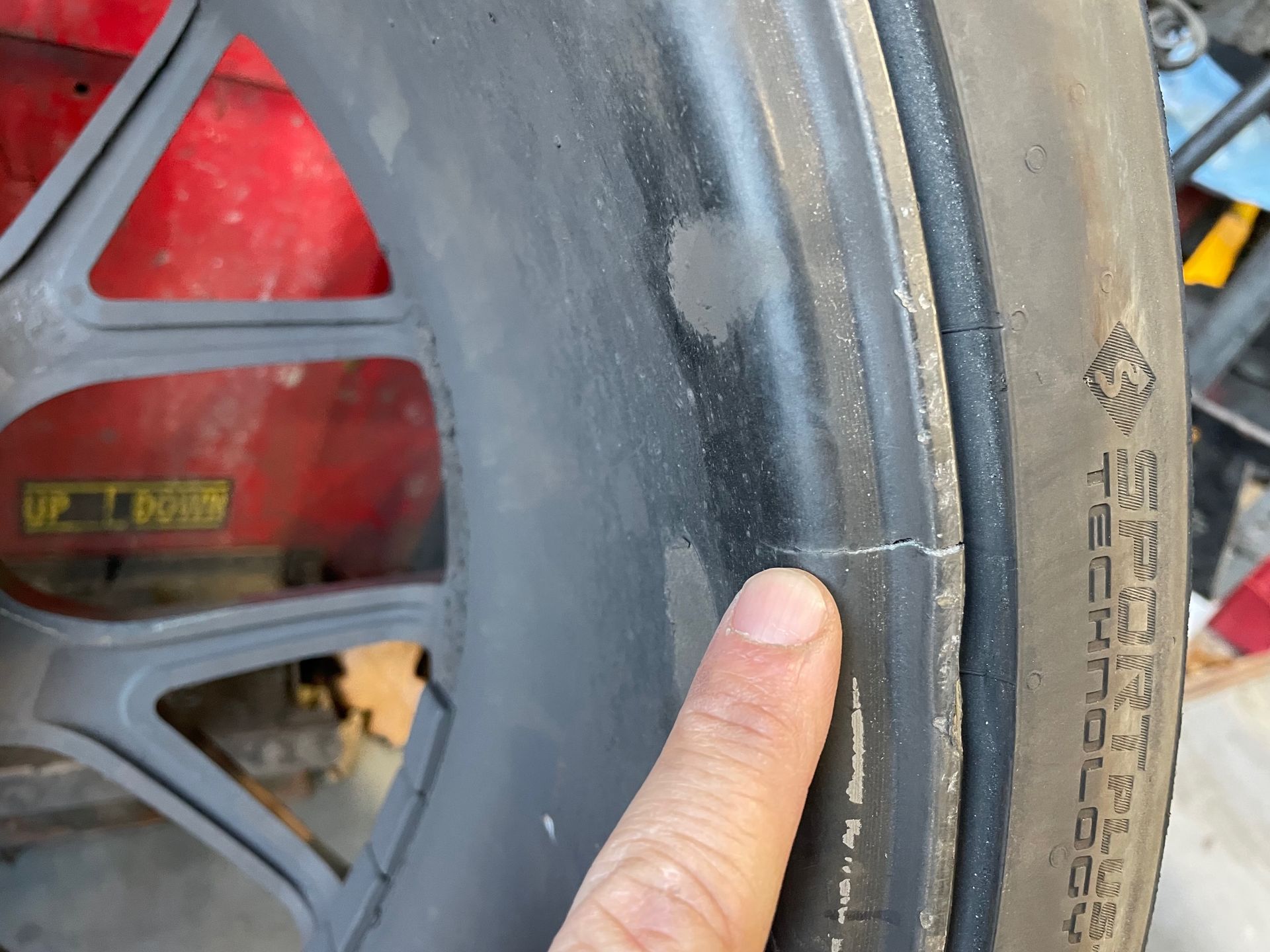 A person is pointing at a tire that has the word technology on it