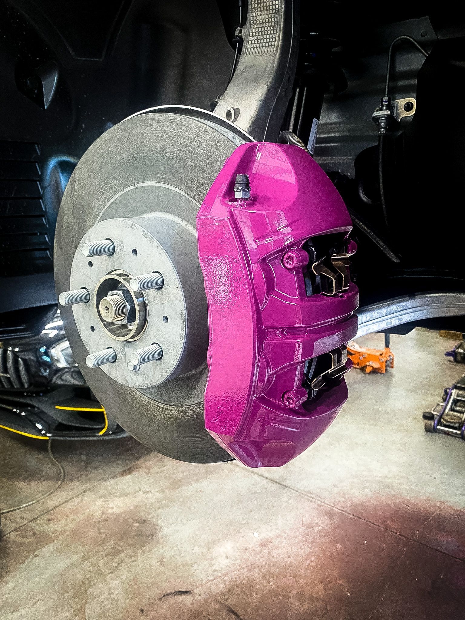 A close up of a pink brake caliper on a car.