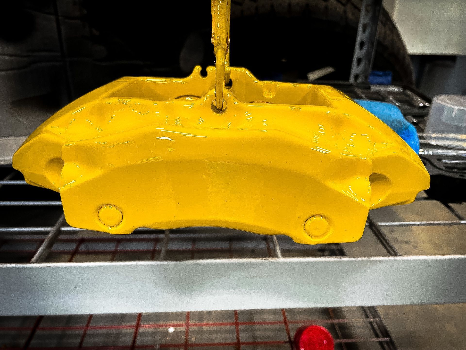 A yellow brake caliper is sitting on top of a metal shelf.