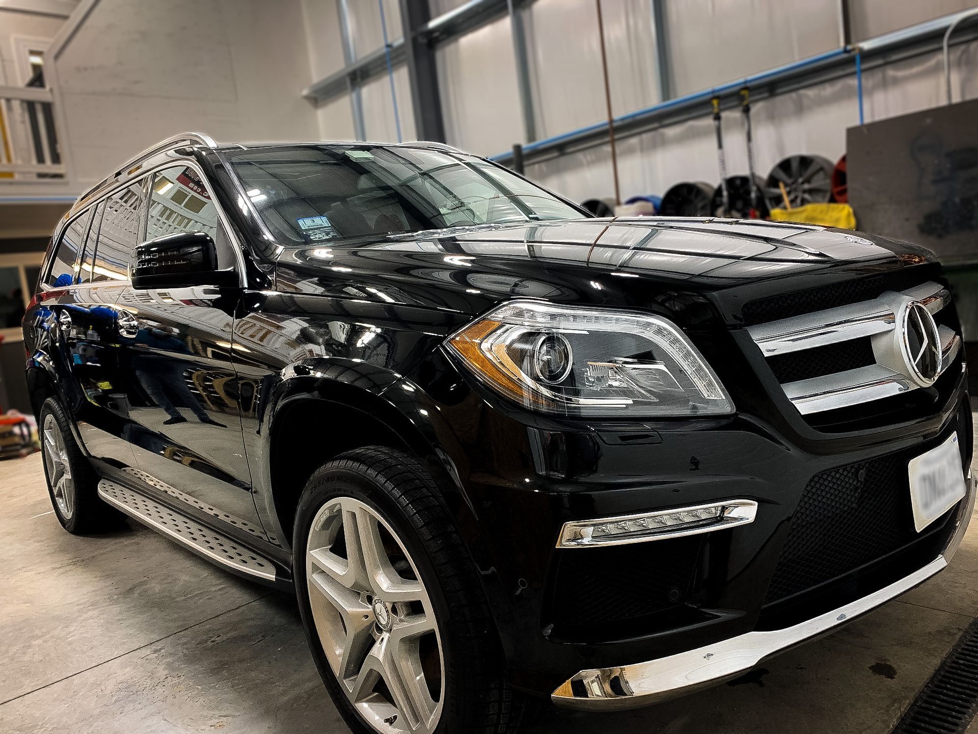 A black mercedes benz gl 550 is parked in a garage.