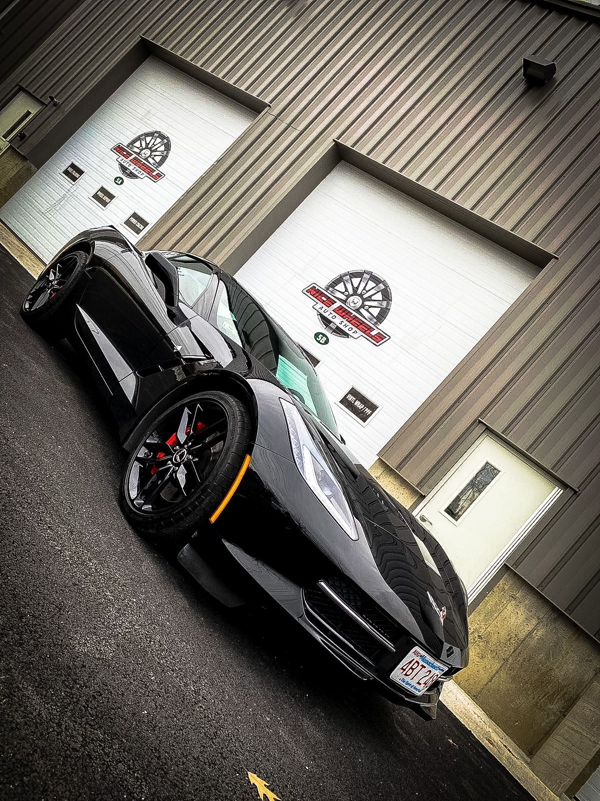 A black sports car is parked in front of a garage door.