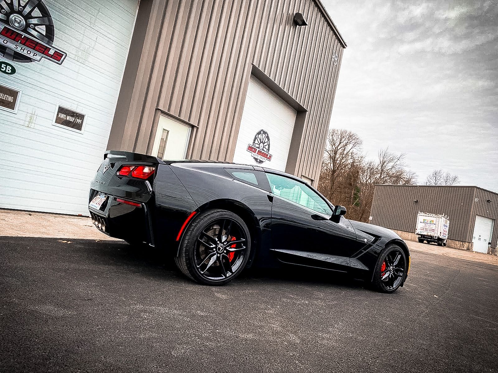 A black sports car is parked in front of a building.