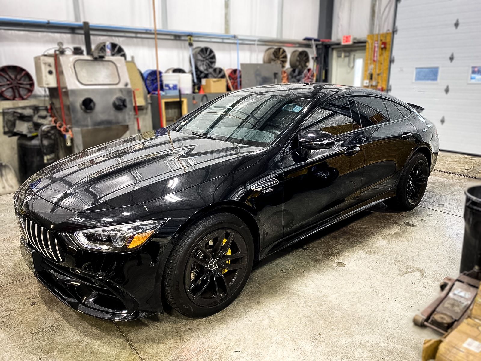 A black car is parked in a garage next to a garage door.