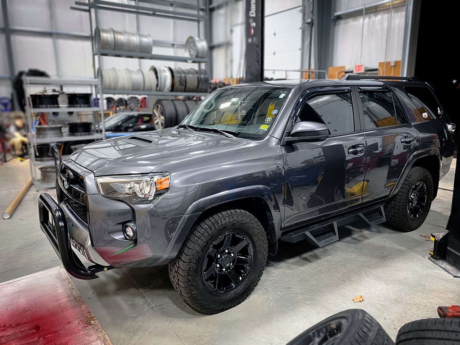 A toyota 4runner is parked in a garage next to tires.