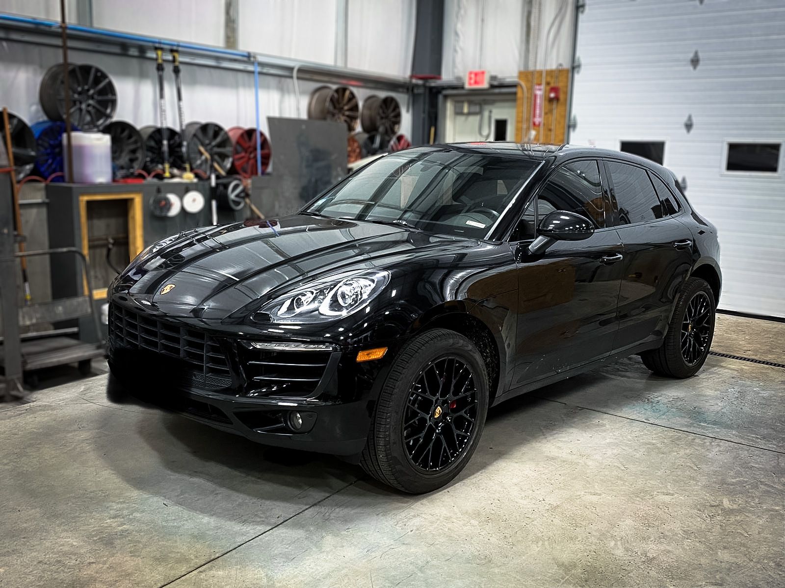 A black porsche macan is parked in a garage.