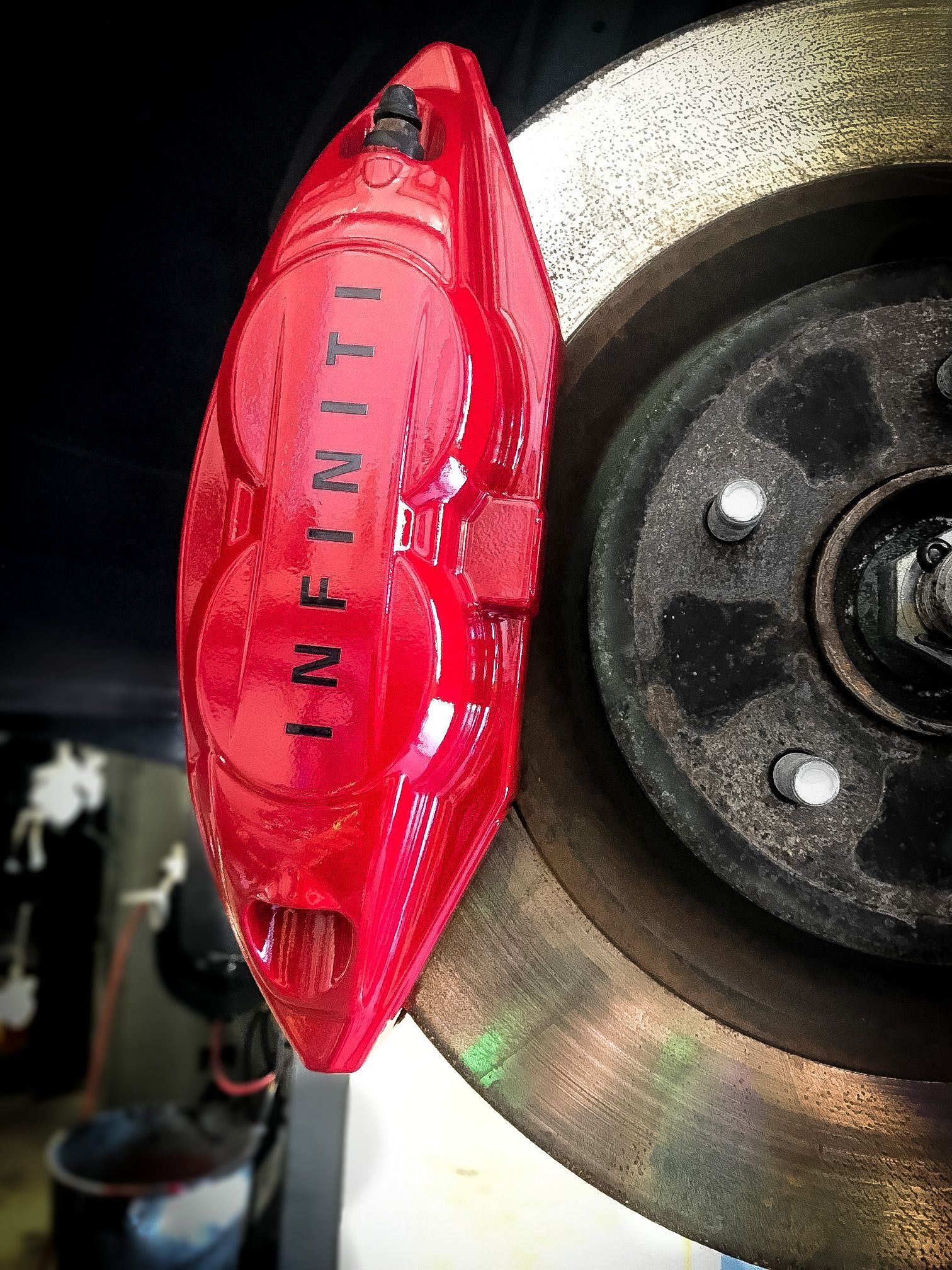 A red infiniti brake caliper is on a brake disc