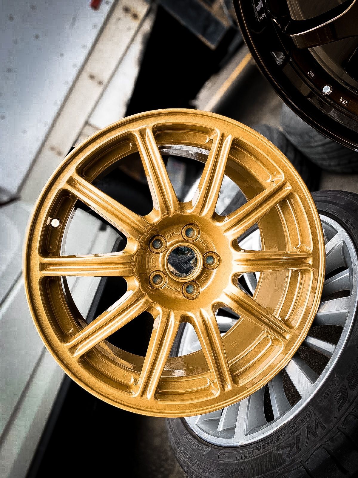 A gold rim is sitting on top of a pile of silver rims.